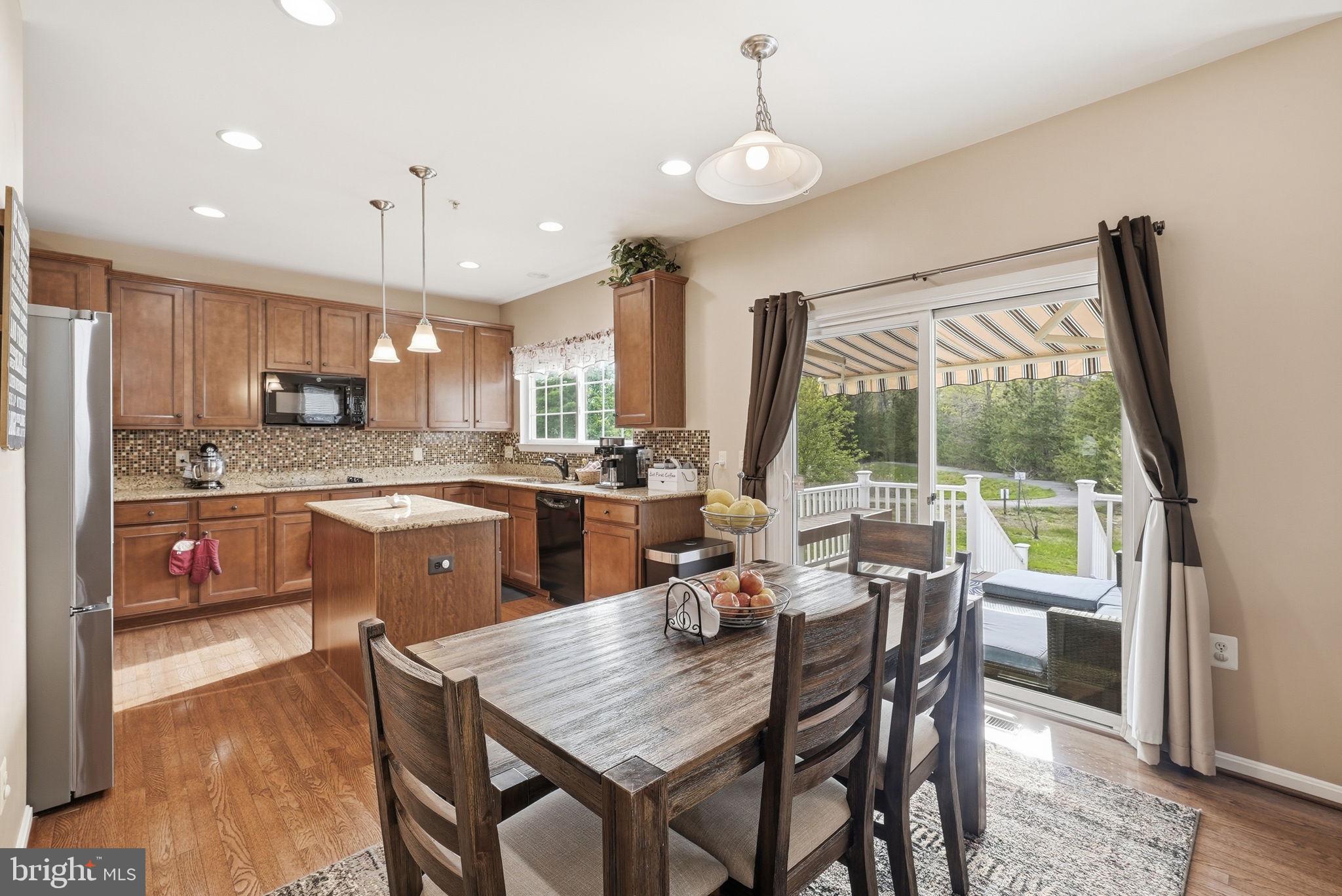 6900 Lenape Court Brandywine, MD 20613 - Photo 10 of 43 a dining room with stainless steel appliances granite countertop a stove a refrigerator a sink dishwasher a dining table and chairs with wooden floor