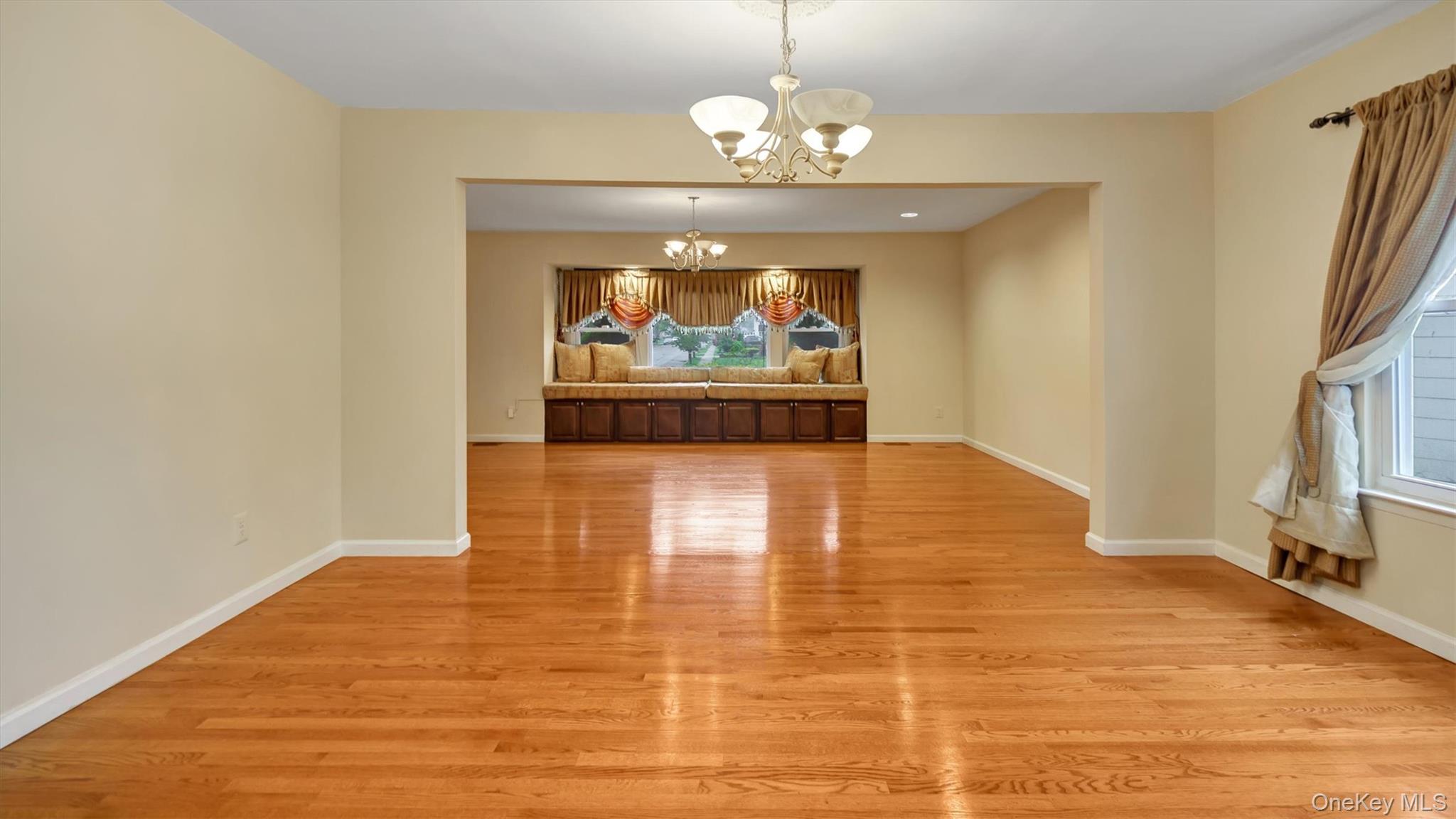 47 Carriage Road Roslyn, NY 11576 - Photo 13 of 31 Unfurnished dining area featuring an inviting chandelier, baseboards, and light wood finished floors