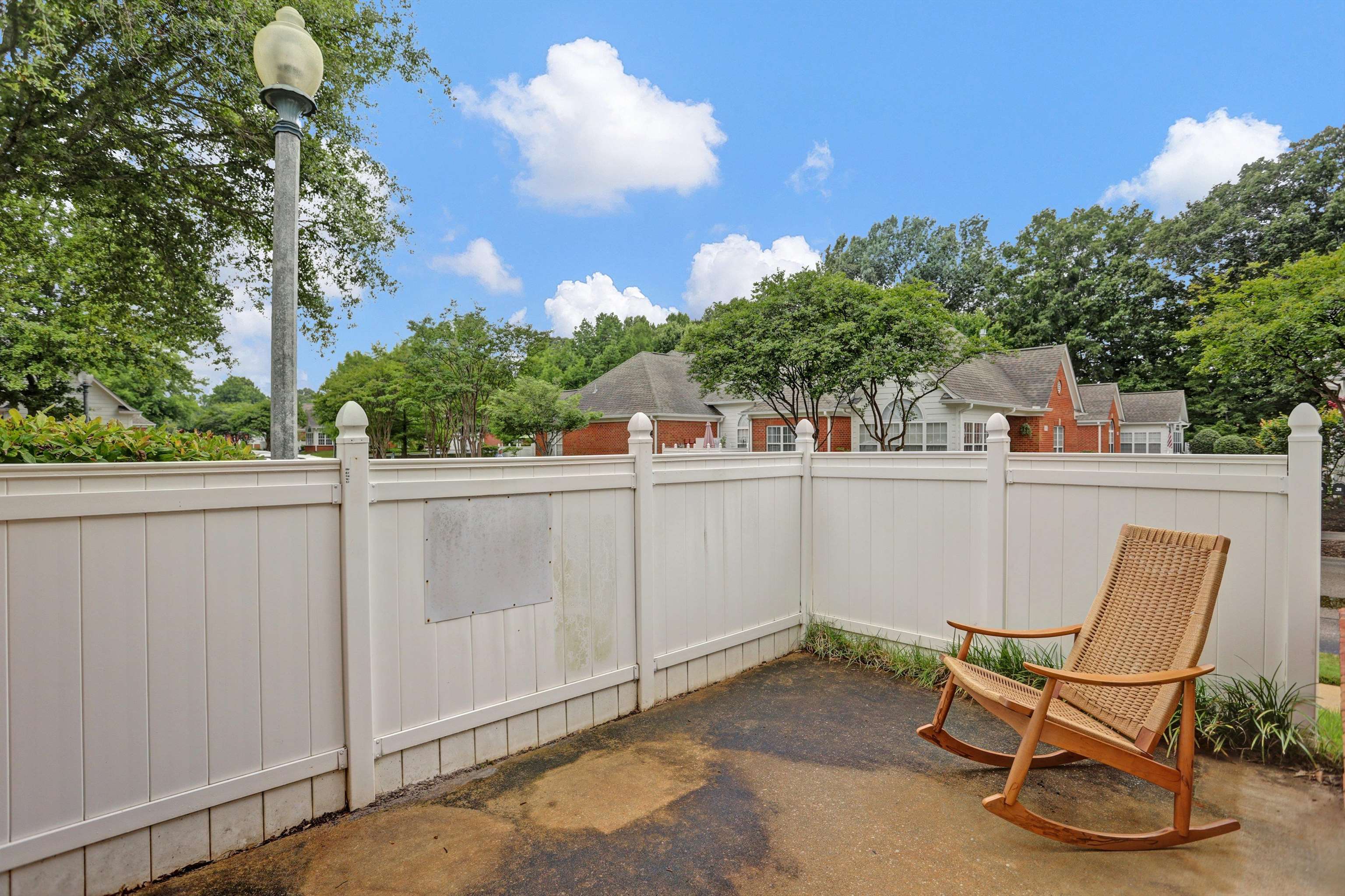 34 Peyton Ridge Drive, Unit 21 Collierville, TN 38017 - Photo 5 of 37 Private patio space featuring a white privacy fence, paved surface, and lush perimeter landscaping