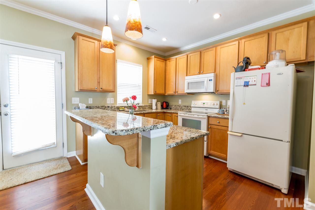 8412 Aztec Dawn Court Raleigh, NC 27613 - Photo 7 of 24 a kitchen with stainless steel appliances granite countertop a refrigerator a sink dishwasher a stove and white countertops with wooden floor