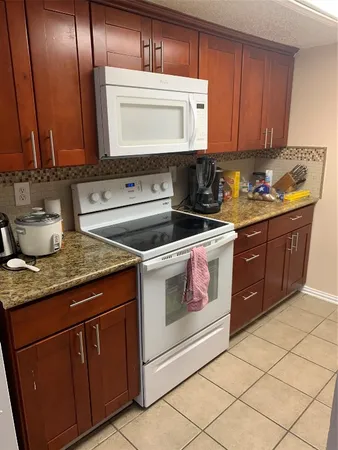 a kitchen with granite countertop a stove sink and cabinets