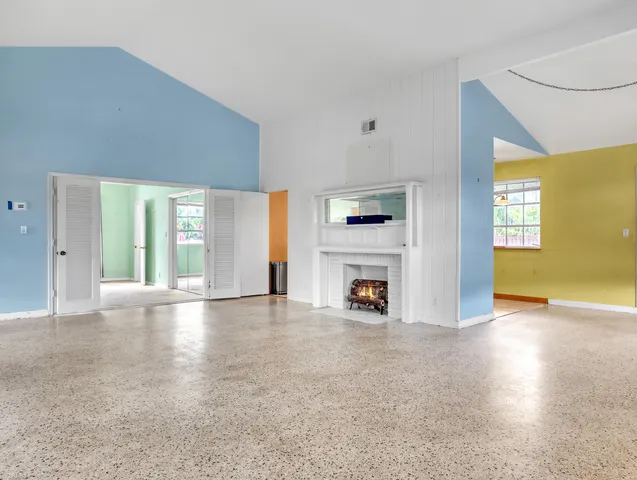 an empty room with windows and fireplace