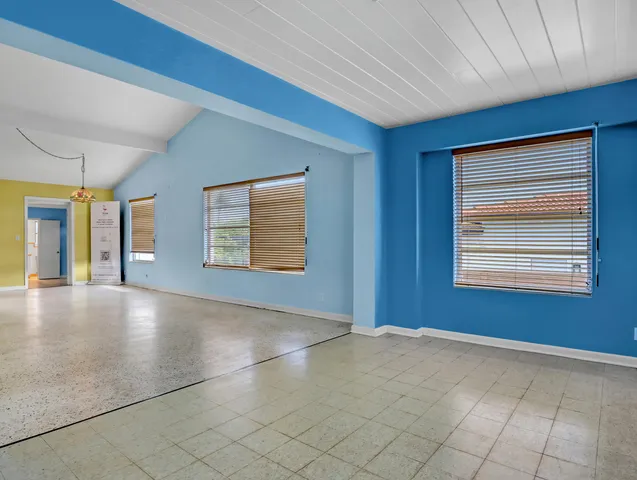 a view of an empty room with window and chandelier fan