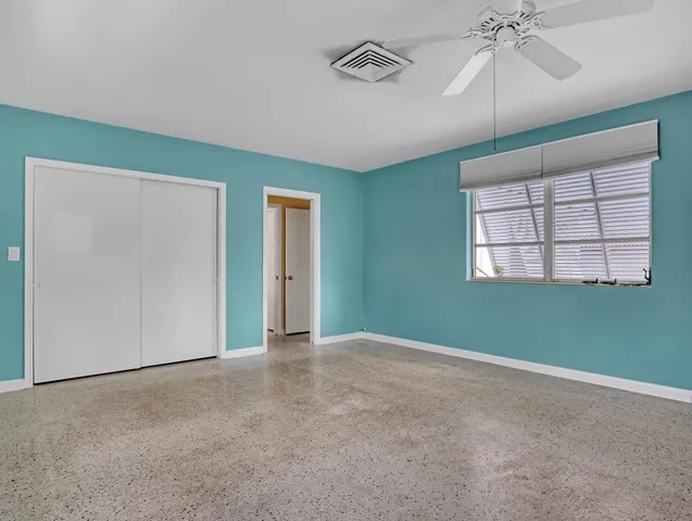 an empty room with windows and fan