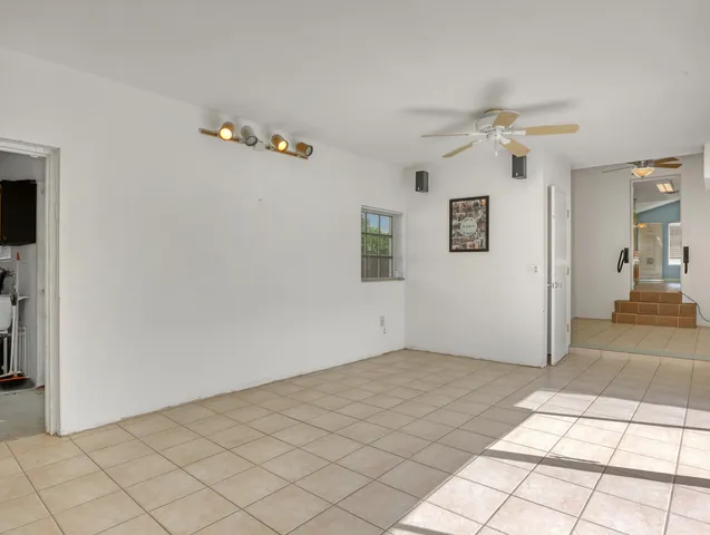 a view of an empty room and chandelier fan