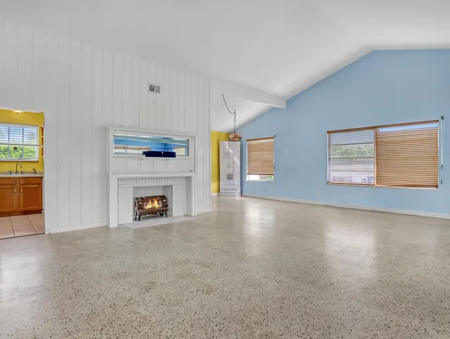 an empty room with windows and fireplace