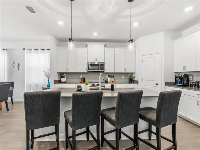 a kitchen with stainless steel appliances a table chairs refrigerator and microwave