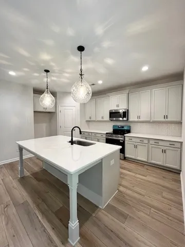 a kitchen with kitchen island granite countertop a sink a stove and cabinets
