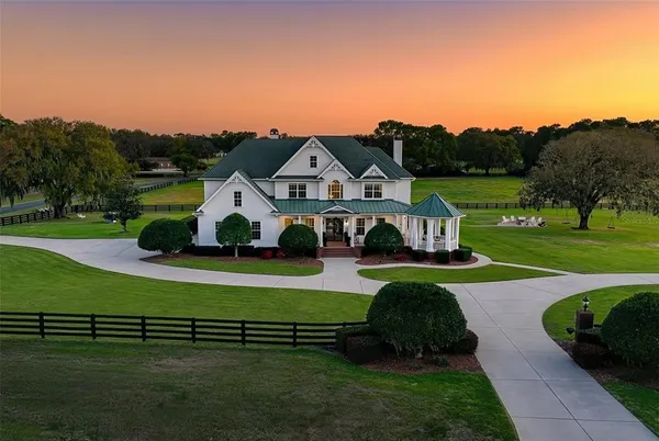 a front view of a house with a garden and lake view