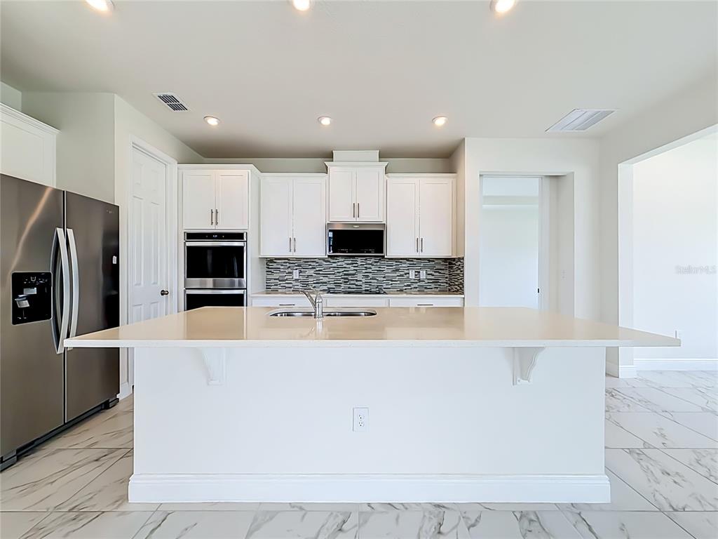 16822 Wingspread Loop Winter Garden, FL 34787 - Photo 13 of 47 a large kitchen with stainless steel appliances a large counter top and a stove top oven