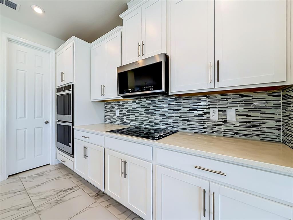 16822 Wingspread Loop Winter Garden, FL 34787 - Photo 15 of 47 a kitchen with granite countertop white cabinets stainless steel appliances and a counter space