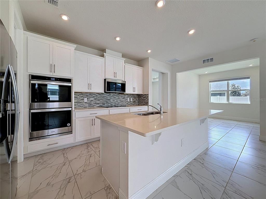 16822 Wingspread Loop Winter Garden, FL 34787 - Photo 19 of 47 a kitchen with stainless steel appliances granite countertop a sink and a stove top oven with white cabinets