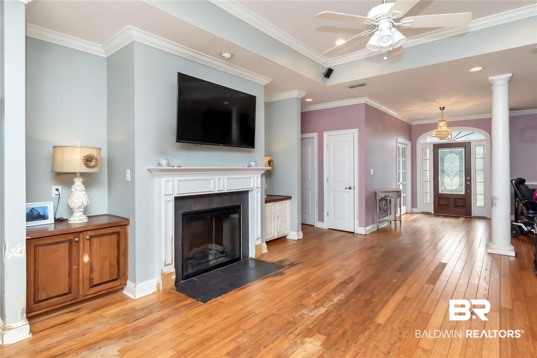 7170 Pierson Drive Mobile, AL 36619 - Photo 4 of 29 Unfurnished living room featuring ceiling fan, ornamental molding, ornate columns, and light hardwood / wood-style floors