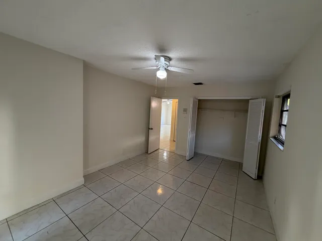a view of an empty room with a ceiling fan and a window