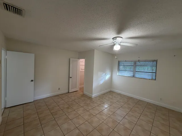 a view of an empty room with window and chandelier fan
