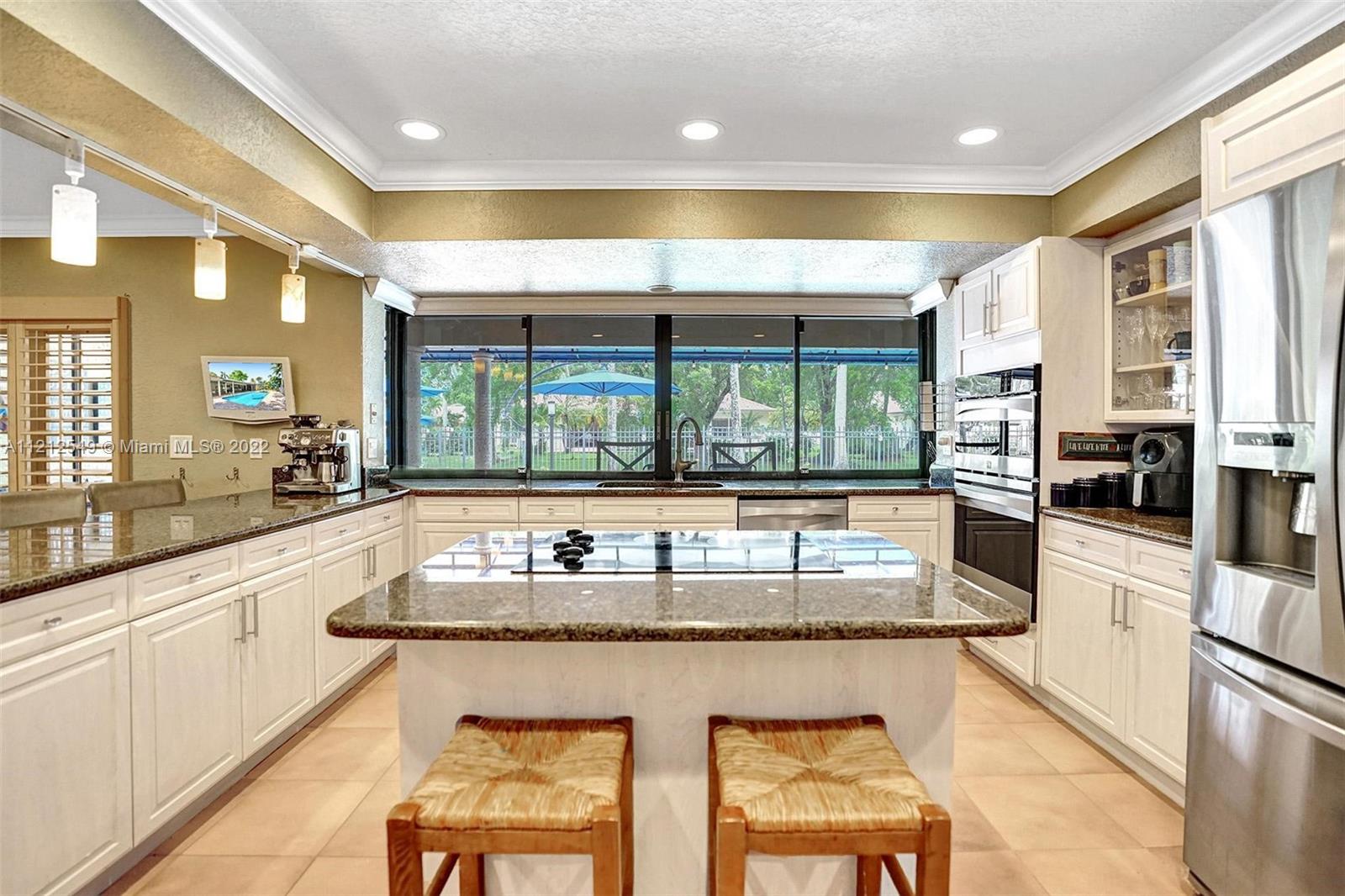 7360 Southwest 16th Street Plantation, FL 33317 - Photo 37 of 70 a kitchen with stainless steel appliances granite countertop a stove a sink and a granite counter tops with white cabinets next to a window