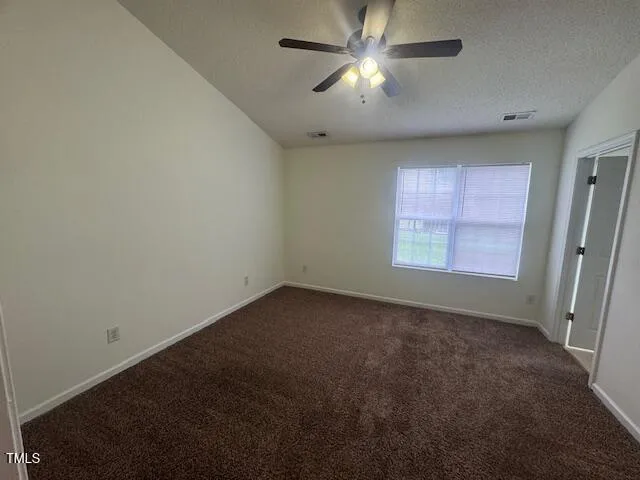 an empty room with a window and a fan