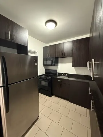 a kitchen with granite countertop a refrigerator and a stove top oven
