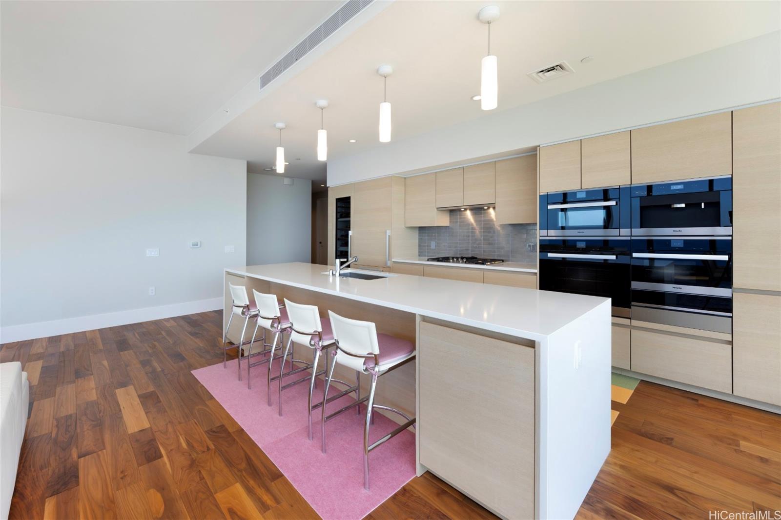 1108 Auahi Street, Unit 3300 Honolulu, HI 96814 - Photo 12 of 25 a kitchen with kitchen island a stove a table and chairs in it