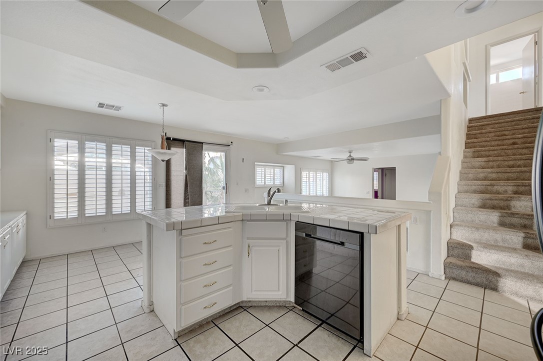 8776 Country View Avenue Las Vegas, NV 89129 - Photo 13 of 43 Kitchen with ceiling fan, white cabinets, tile counters, and dishwasher