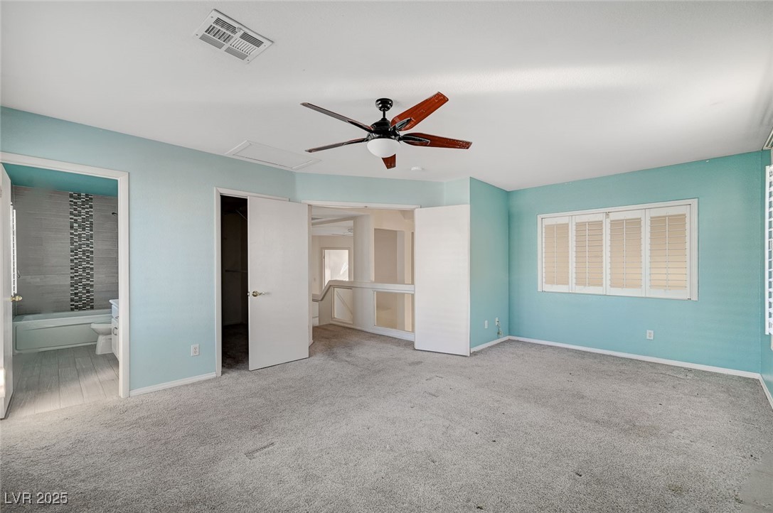 8776 Country View Avenue Las Vegas, NV 89129 - Photo 21 of 43 Unfurnished bedroom featuring a walk in closet, light carpet, ceiling fan, and ensuite bath