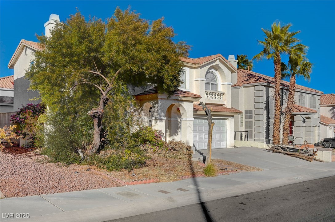 8776 Country View Avenue Las Vegas, NV 89129 - Photo 3 of 43 Mediterranean / spanish house featuring driveway, stucco siding, an attached garage, and a chimney