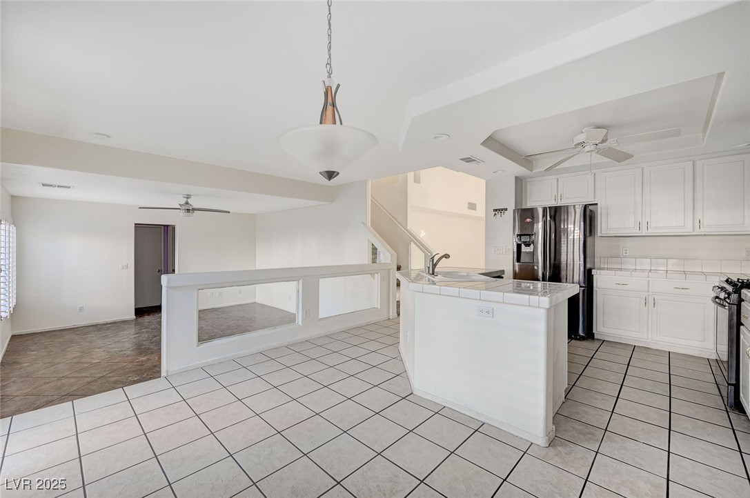 8776 Country View Avenue Las Vegas, NV 89129 - Photo 10 of 43 Kitchen with a ceiling fan, tile countertops, decorative light fixtures, white cabinets, and a raised ceiling