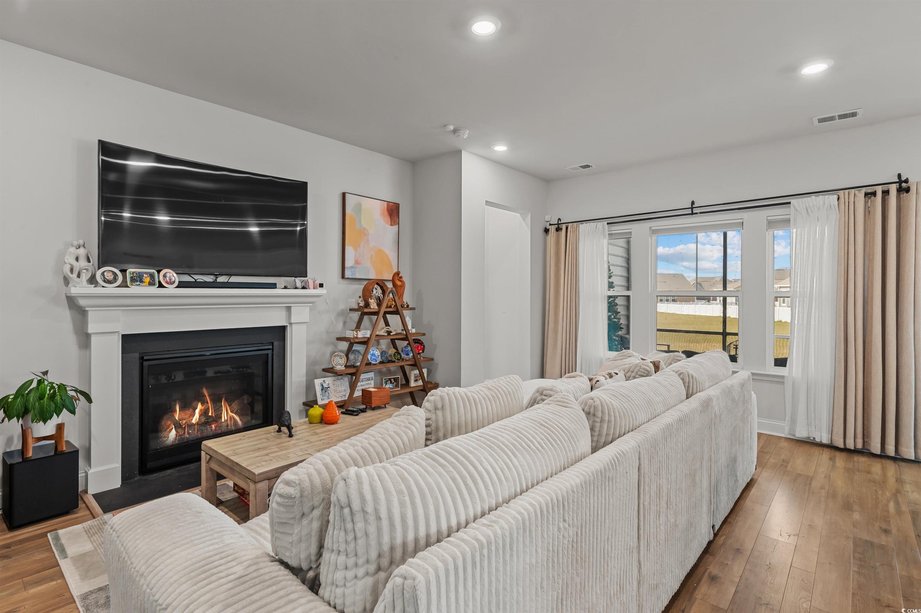 1176 HARBISON Circle Myrtle Beach, SC 29579 - Photo 14 of 40 Living area featuring a fireplace with flush hearth, visible vents, recessed lighting, and wood-type flooring
