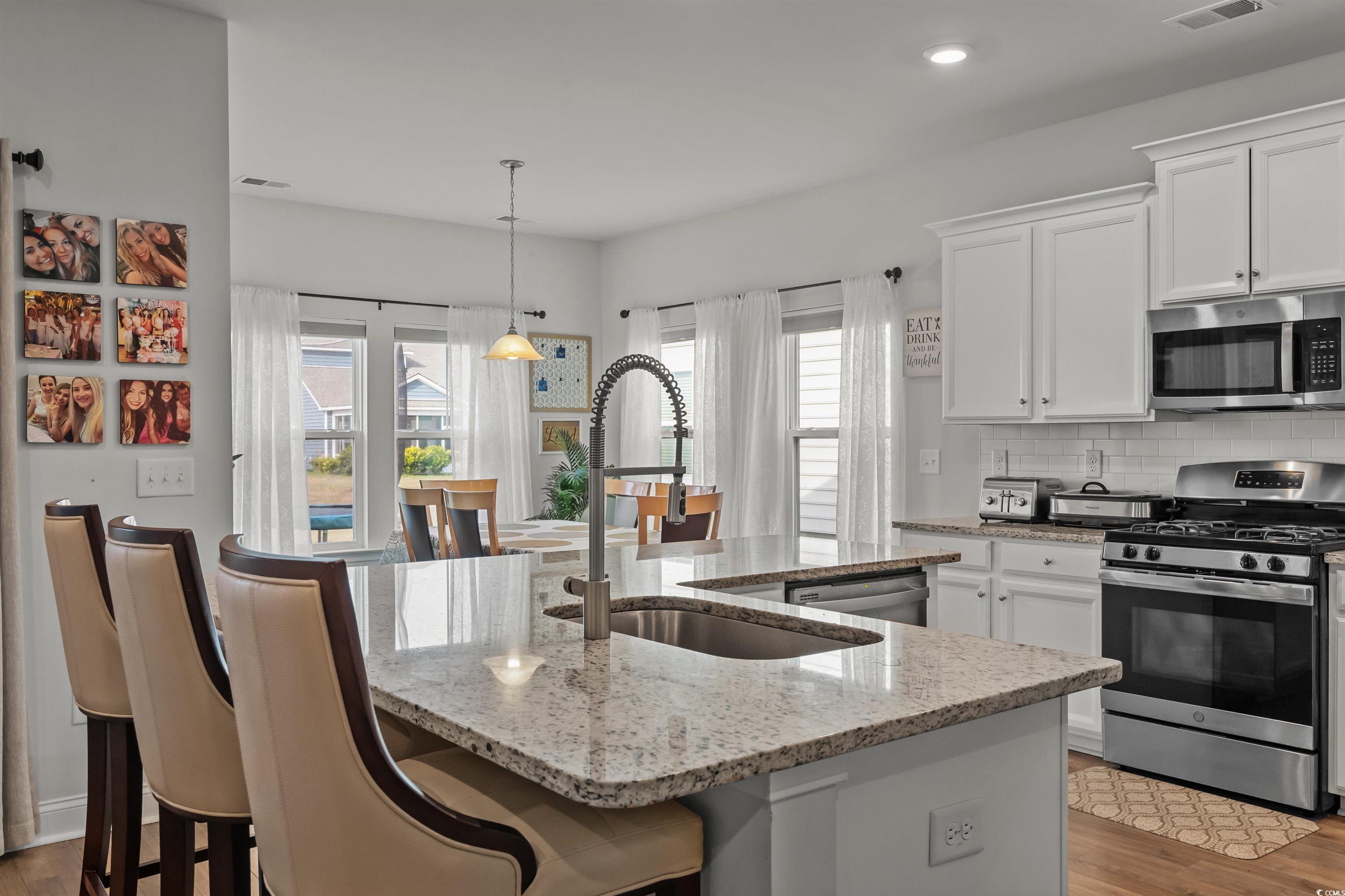 1176 HARBISON Circle Myrtle Beach, SC 29579 - Photo 15 of 40 Kitchen with decorative backsplash, stainless steel appliances, a center island with sink, a sink, and light stone counters
