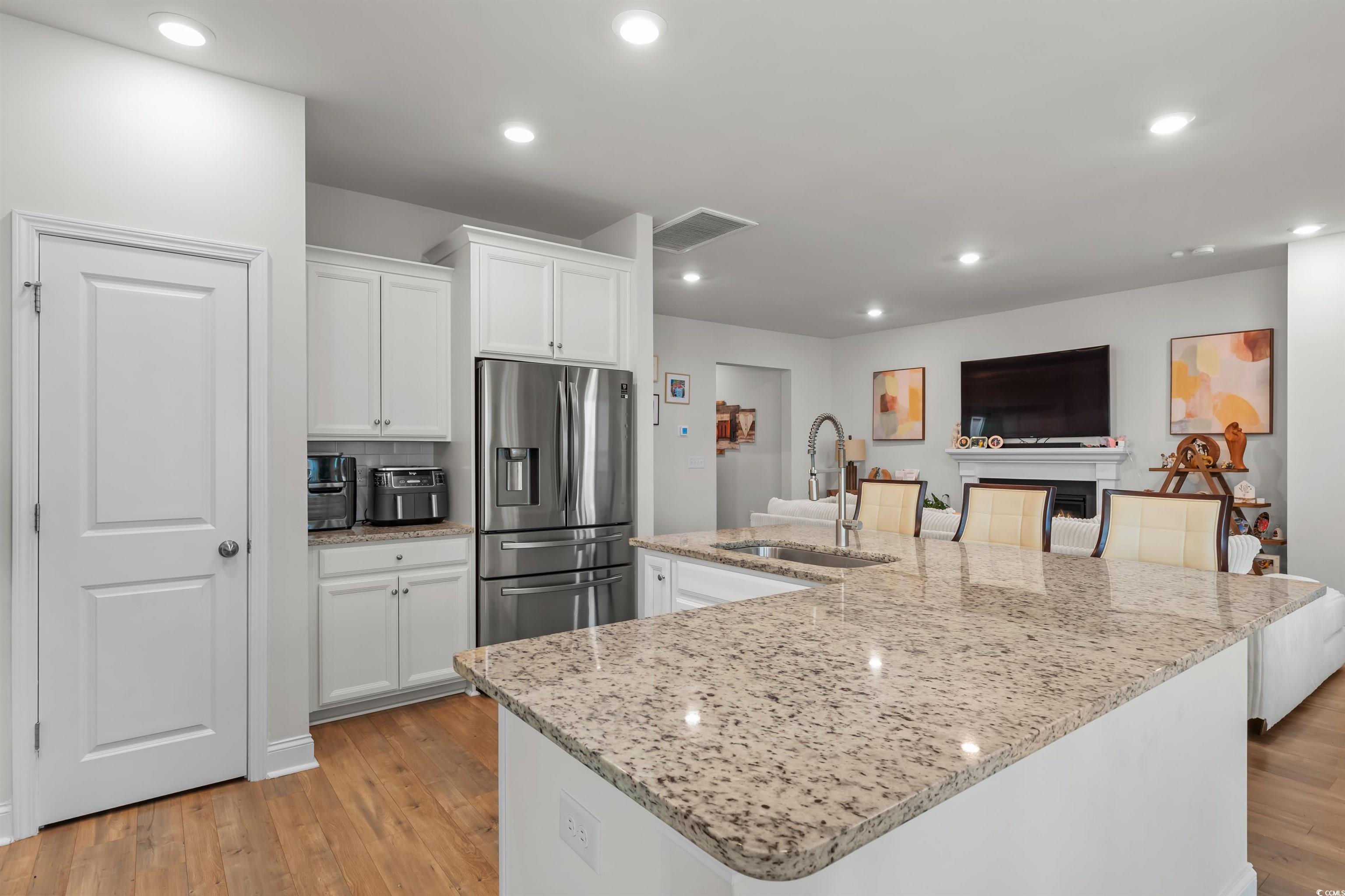 1176 HARBISON Circle Myrtle Beach, SC 29579 - Photo 17 of 40 Kitchen featuring a sink, light wood finished floors, stainless steel fridge, visible vents, and white cabinets