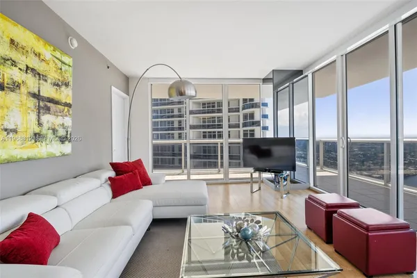 a living room with furniture a rug and a floor to ceiling window