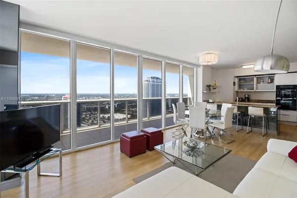 a living room with furniture a flat screen tv and a floor to ceiling window