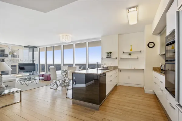 a large kitchen with stainless steel appliances a stove a sink dishwasher and a dining table with wooden floor