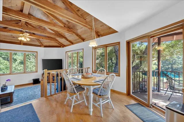 a view of a patio with table and chairs under an umbrella with large trees