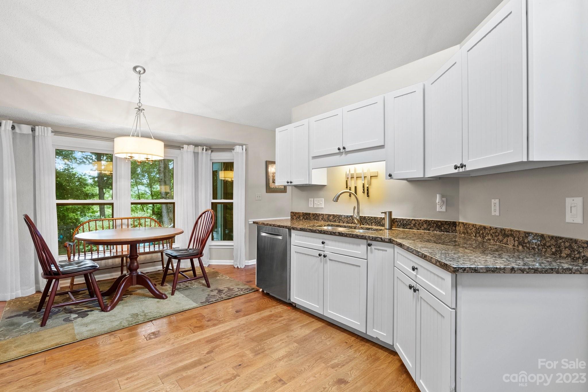 6 Holly Ridge Court Arden, NC 28704 - Photo 9 of 27 a open kitchen with granite countertop a stove a sink white cabinets with a dining table and chairs