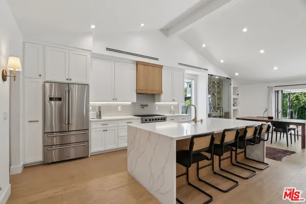 a kitchen with a refrigerator a stove a sink and a dining table with chairs