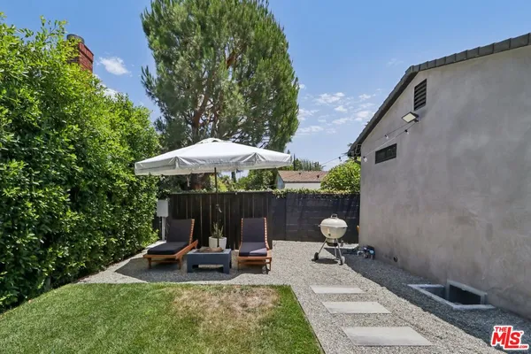 a view of a backyard with chairs and umbrella