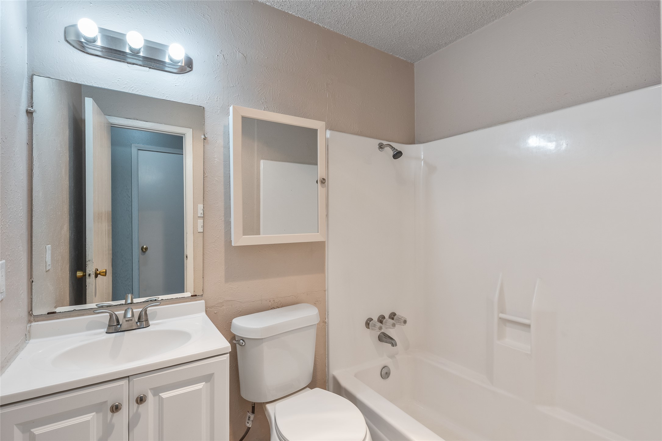1111 West Rundberg Lane Austin, TX 78758 - Photo 6 of 16 A well-lit bathroom features a white vanity, a clean toilet, and a combined tub and shower.