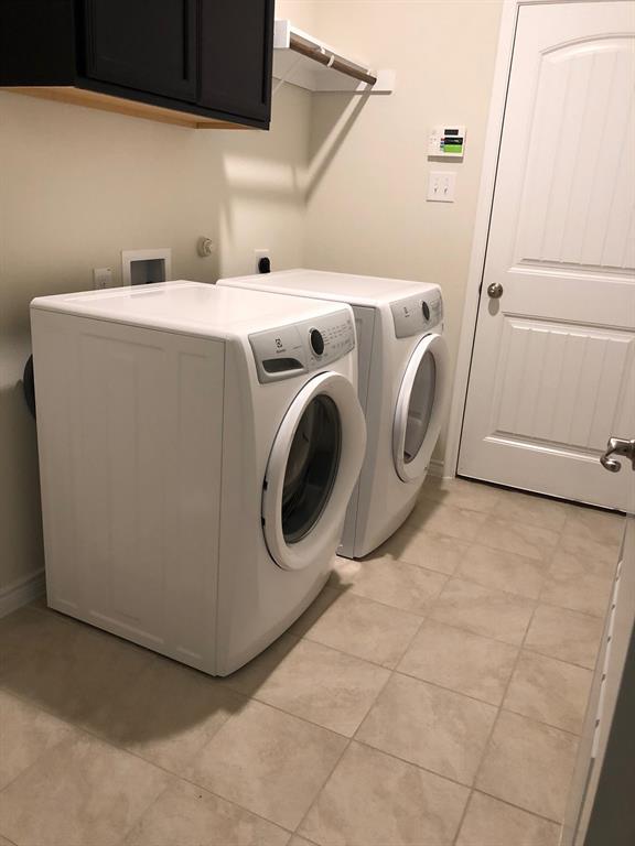 1732 Beasley Street Van Alstyne, TX 75495 - Photo 13 of 17 Laundry area featuring cabinet space, light tile patterned floors, and washing machine and dryer