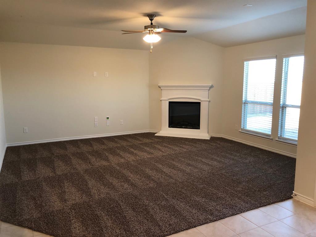 1732 Beasley Street Van Alstyne, TX 75495 - Photo 2 of 17 Unfurnished living room with a fireplace with raised hearth, lofted ceiling, ceiling fan, light colored carpet, and light tile patterned floors