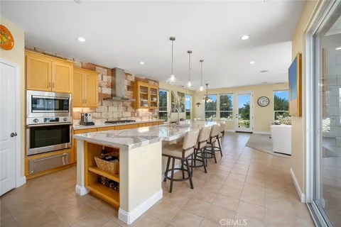 a kitchen with stainless steel appliances kitchen island granite countertop a table chairs and a refrigerator