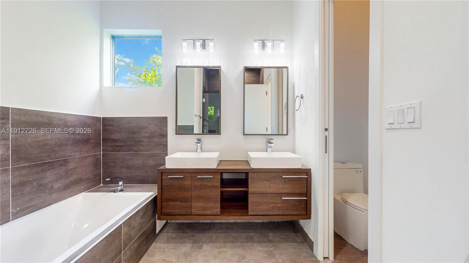 3461 Southwest 25th Street, Unit A Miami, FL 33133 - Photo 12 of 27 a bathroom with a double vanity sink and mirror