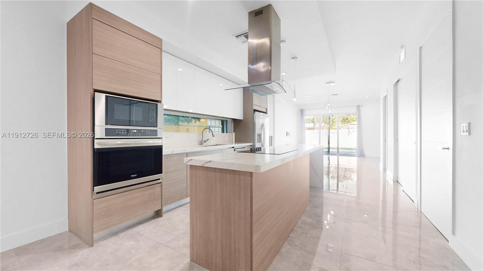 3461 Southwest 25th Street, Unit A Miami, FL 33133 - Photo 5 of 27 a kitchen with stainless steel appliances kitchen island granite countertop a stove a sink and a microwave
