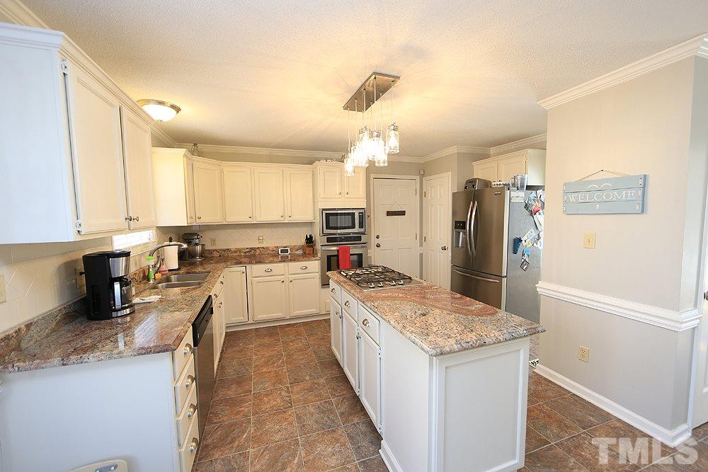 5029 Denham Court Raleigh, NC 27613 - Photo 5 of 13 a large kitchen with a stove a refrigerator a sink dishwasher and white cabinets with wooden floor
