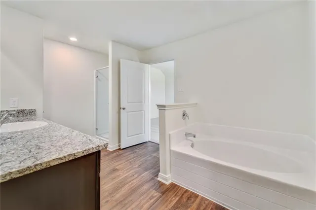 a bathroom with a granite countertop sink and a bathtub