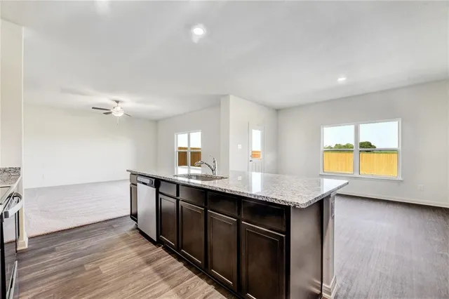 a kitchen with stainless steel appliances granite countertop a sink cabinets and wooden floor