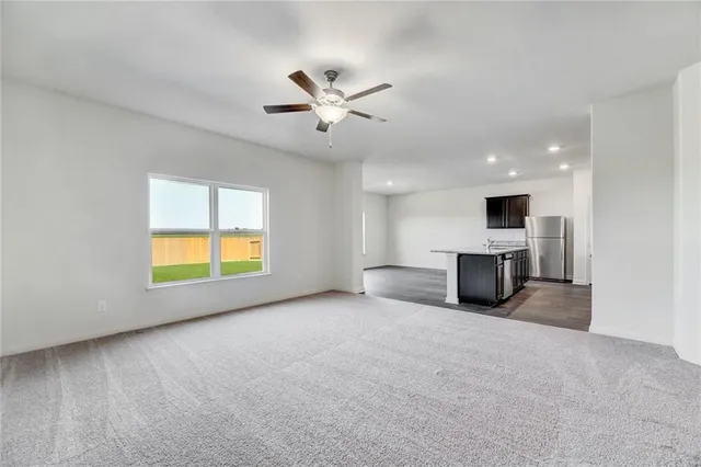 a view of an empty room with a kitchen and a window