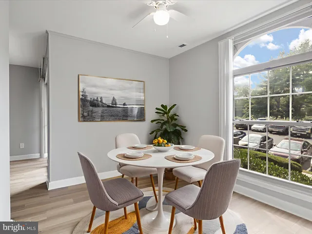 a dining room with furniture a large window and potted plants