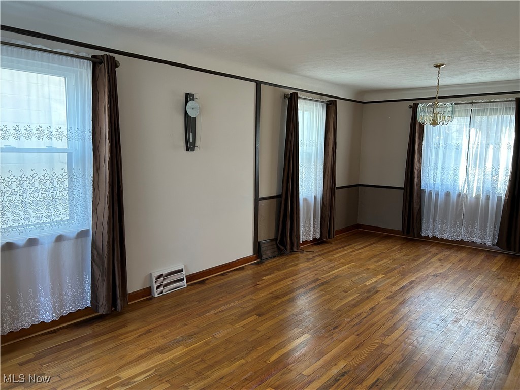 1094 Plainfield Road Cleveland, OH 44121 - Photo 12 of 41 Living Room
chandelier, a healthy amount of sunlight, dark hardwood / wood-style flooring, and a textured ceiling