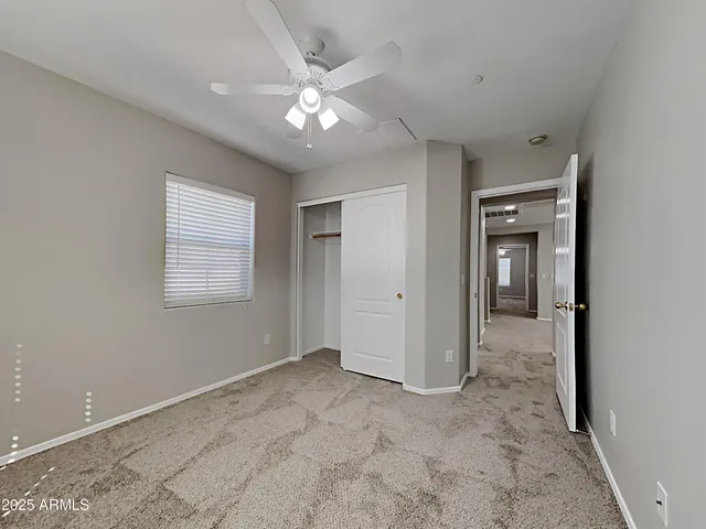 a view of an empty room with chandelier fan
